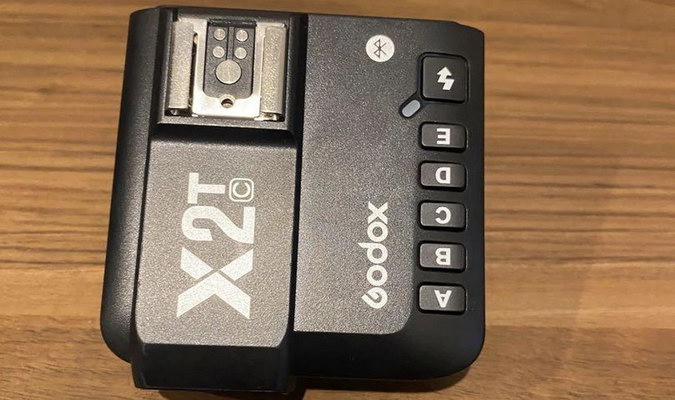 Верхня панель трансмітера Godox X2T-C із наскрізним металевим гарячим башмаком і п’ятьма кнопками вибору груп